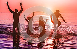 Happy friends jumping inside water on tropical beach at sunset - Group of young people having fun on summer vacation - Youth,