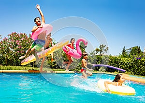 Happy friends jumping in pool on the vacations