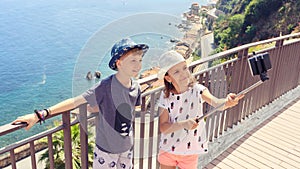 Happy friends kids taking selfie in beautiful town of Scilla Italy, smiling children having fun together sharing pictures online