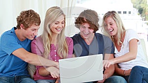Happy friends laughing in front of a laptop