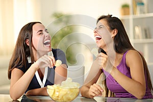Happy friends laughing hilariously eating potato chips photo