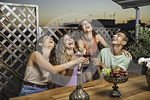 Happy Friends Laughing Loud and Toasting Red Wine Together with White and Red black Grapes on the Table.