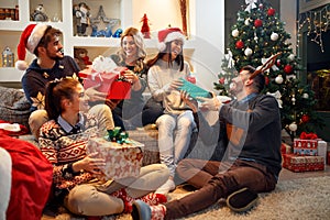 Happy friends laughing and sharing Christmas gifts