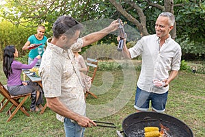 Happy friends laughing and toasting with a big smile around the barbecue. Smiling people eating on the patio of the