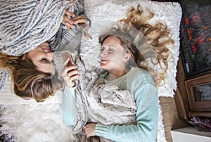 Happy friends laying on blankets with phones laughing