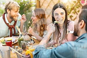 Happy friends lunching with healthy food in bar restaurant - Young people having brunch meal eating and drinking smoothies