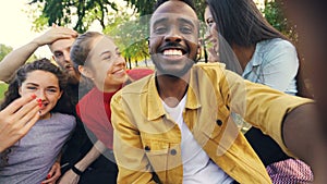 Happy friends are making online video call looking at camera, talking and laughing while African American man is holding