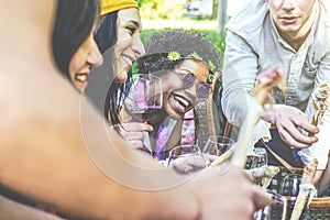 Happy friends making a picnic in a park outdoor - Young people enjoying time together drinking red wine