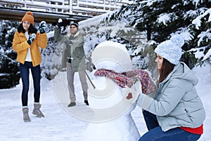 Happy friends making snowman. Winter vacation