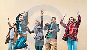 Happy friends millennials jumping against brick wall - Friendship lifestyle and team concept with young millenial peoplehaving fun