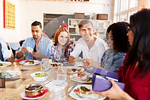 Happy friends with money paying at restaurant