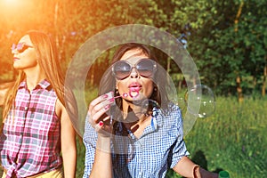 Happy friends in the park on a sunny day . Summer lifestyle portrait of three hipster women enjoy nice day, wearing bright sunglas