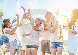 Happy friends partying with colorful powder cloud at holi festival in summer time - Young people having fun on the beach party -