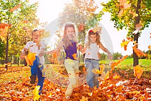 Happy friends play with colorful leaves in forest