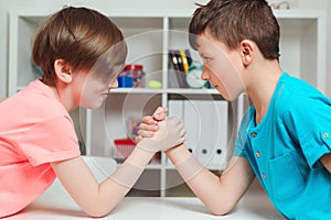 Happy friends playing arm wrestle looking at each other. Cute brothers spending time together at home