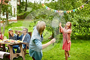 Happy friends playing badminton at summer garden