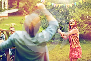 Happy friends playing badminton at summer garden