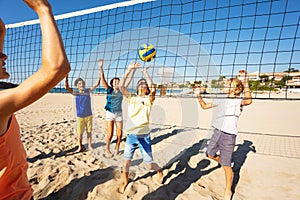 Happy friends playing beach volleyball in summer
