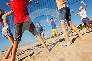 Happy friends playing beach volleyball in summer