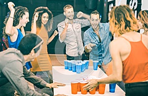 Happy friends playing beer pong in youth hostel - Travel and joy concept with backpackers having unplugged fun at guesthouse