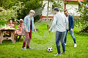 Happy friends playing football at summer garden