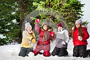 Happy friends playing snowballs at winter forest