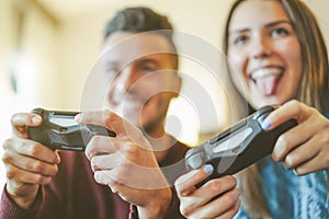 Happy friends playing video games in their apartment - Hilarious young couple having fun with new trend console technology