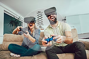 Happy friends playing video games with virtual reality glasses