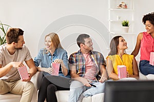 Happy friends with popcorn and tv remote at home