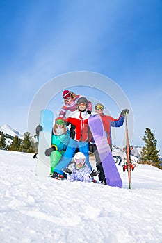 Happy friends posing with snowboards and skis