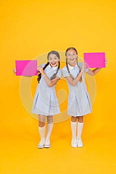 Happy friends in retro uniform. vintage kid fashion. back to school. small girls hold blank paper. encyclopedia book for