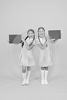 Happy friends in retro uniform. vintage kid fashion. back to school. small girls hold blank paper. encyclopedia book for