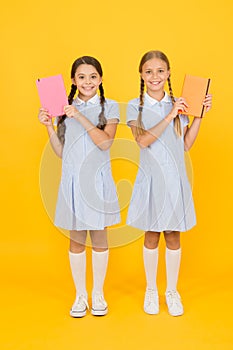 Happy friends in retro uniform. vintage kid fashion. back to school. small girls hold workbook and notepad. encyclopedia