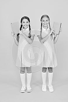 Happy friends in retro uniform. vintage kid fashion. back to school. small girls hold workbook and notepad. encyclopedia