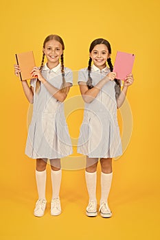 Happy friends in retro uniform. vintage kid fashion. back to school. small girls hold workbook and notepad. encyclopedia