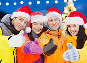 Happy friends in santa hats and ski suits outdoors