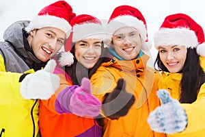 Happy friends in santa hats and ski suits outdoors