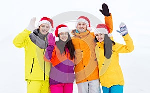 Happy friends in santa hats and ski suits outdoors