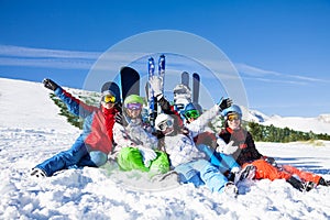 Happy friends sitting with snowboards and skis