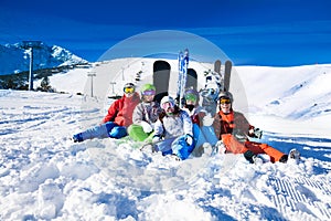 Happy friends sitting with snowboards and skis