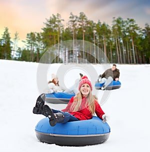 Happy friends sliding down hill on snow tubes