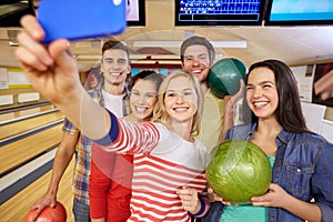 Happy friends with smartphone in bowling club