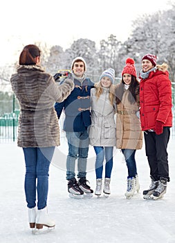 Happy friends with smartphone on ice skating rink