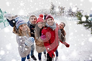 Happy friends with smartphone on ice skating rink