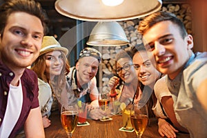 Happy friends with smartphone taking selfie at bar