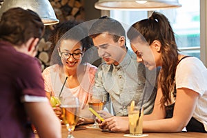 Happy friends with smartphones and drinks at bar