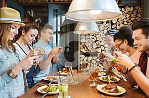 Happy friends with smartphones picturing food