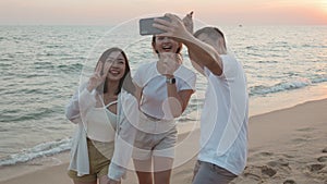 Happy friends smiling and posing taking selfie from smartphone and having fun together on beach