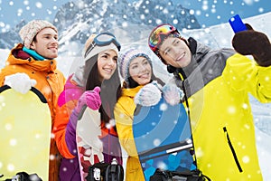 Happy friends with snowboards and smartphone