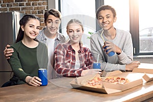 Happy friends spending time together with pizza and soda drinks